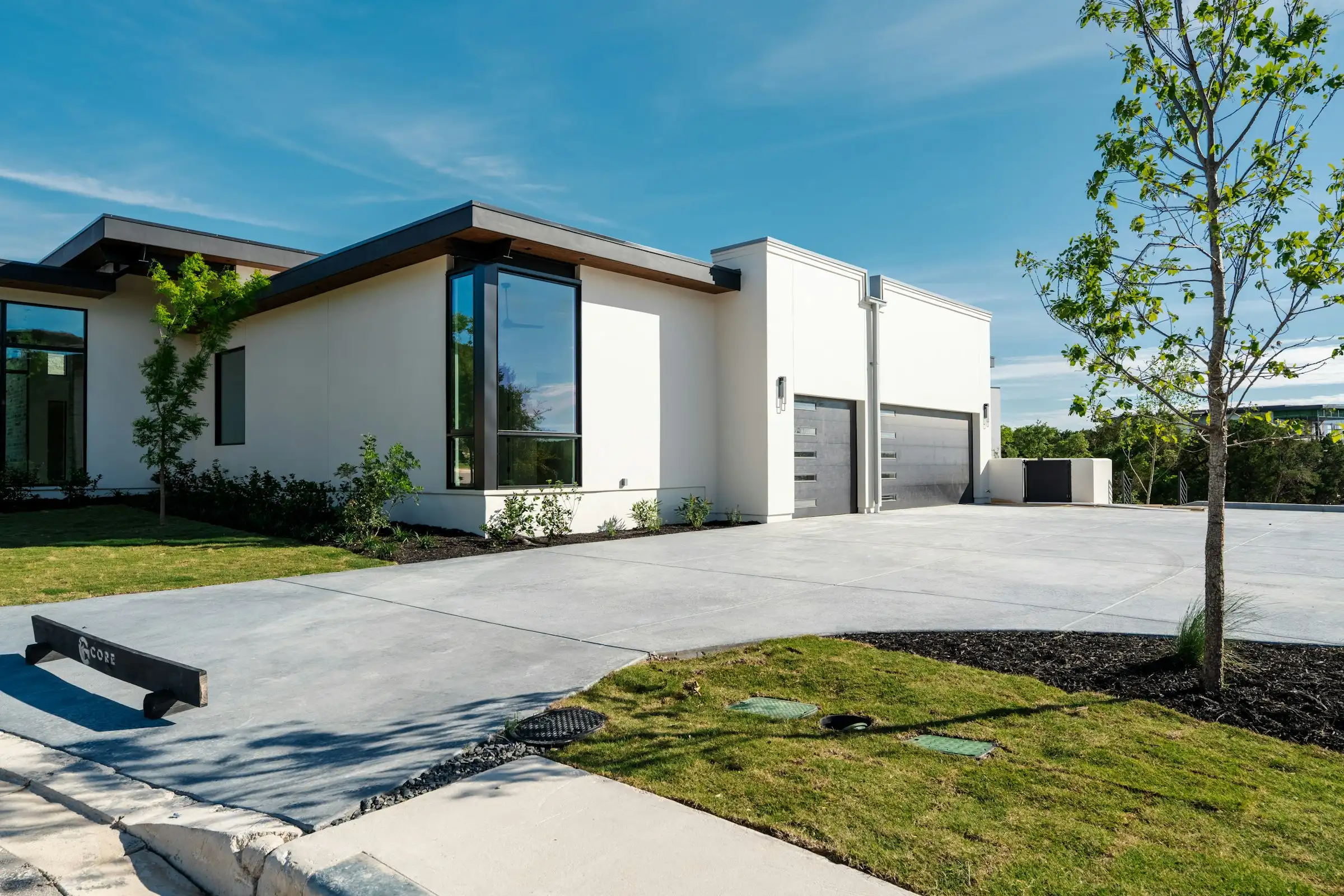 Wide new concrete driveway in front of a modern white house